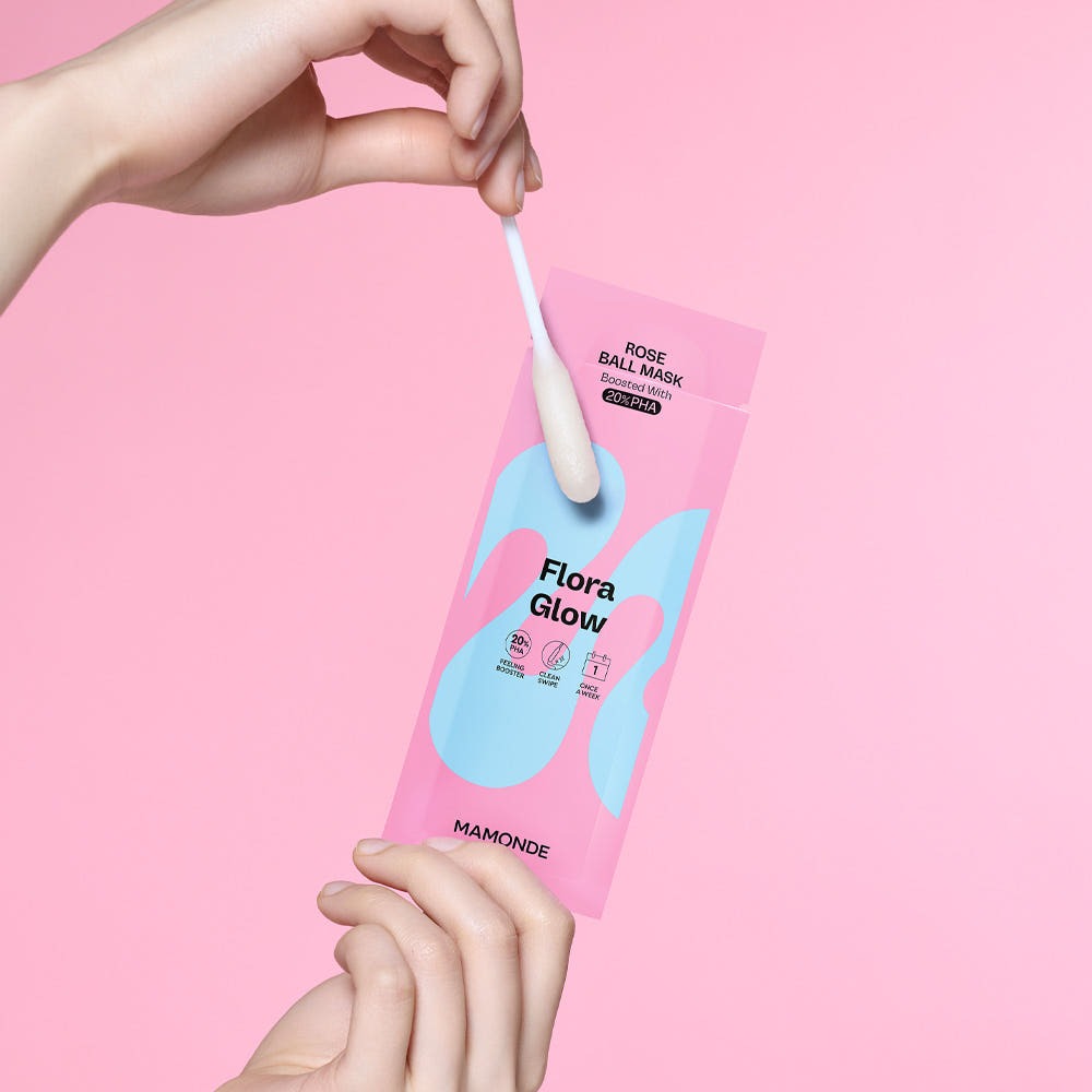 Main tenant MAMONDE Flora Glow Rose Ball Mask 3.5ml : masque rose ball, marque MAMONDE, fond rose pastel, produit beauté