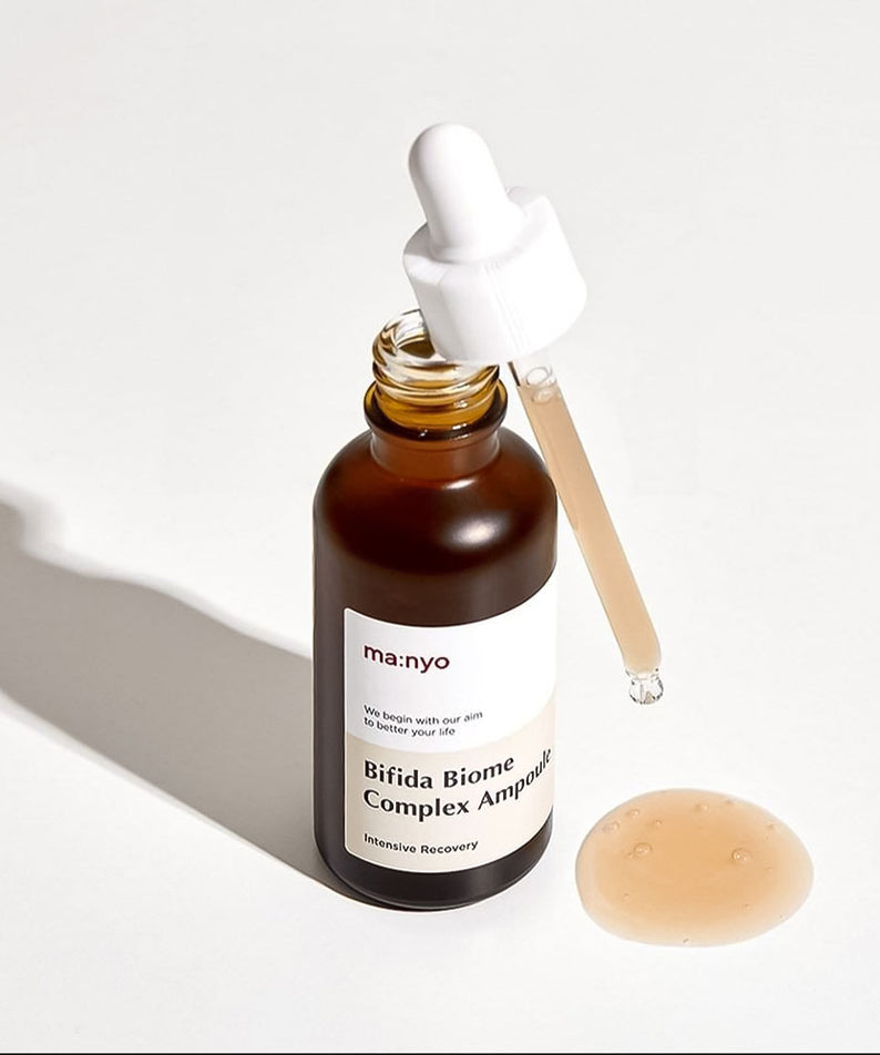 MA:NYO Bifida Biome Complex Ampoule 50m sur fond blanc avec pipette et liquide versé en avant-plan. Flacon marron. Soin intensif de la peau.
