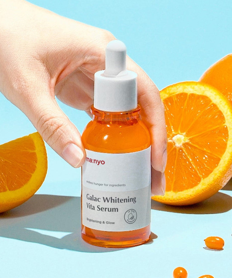 MA:NYO Galac Whitening Vita Serum 50ml, flacon orange en main, agrumes sur fond bleu, sérum éclaircissant de la marque MA:NYO