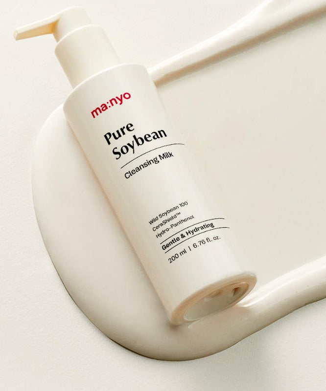 MANYO Pure Soybean Cleansing Milk 200ml se pose sur une surface crèmeuse, bouteille pompe blanche. Soin visage hydratant et doux.