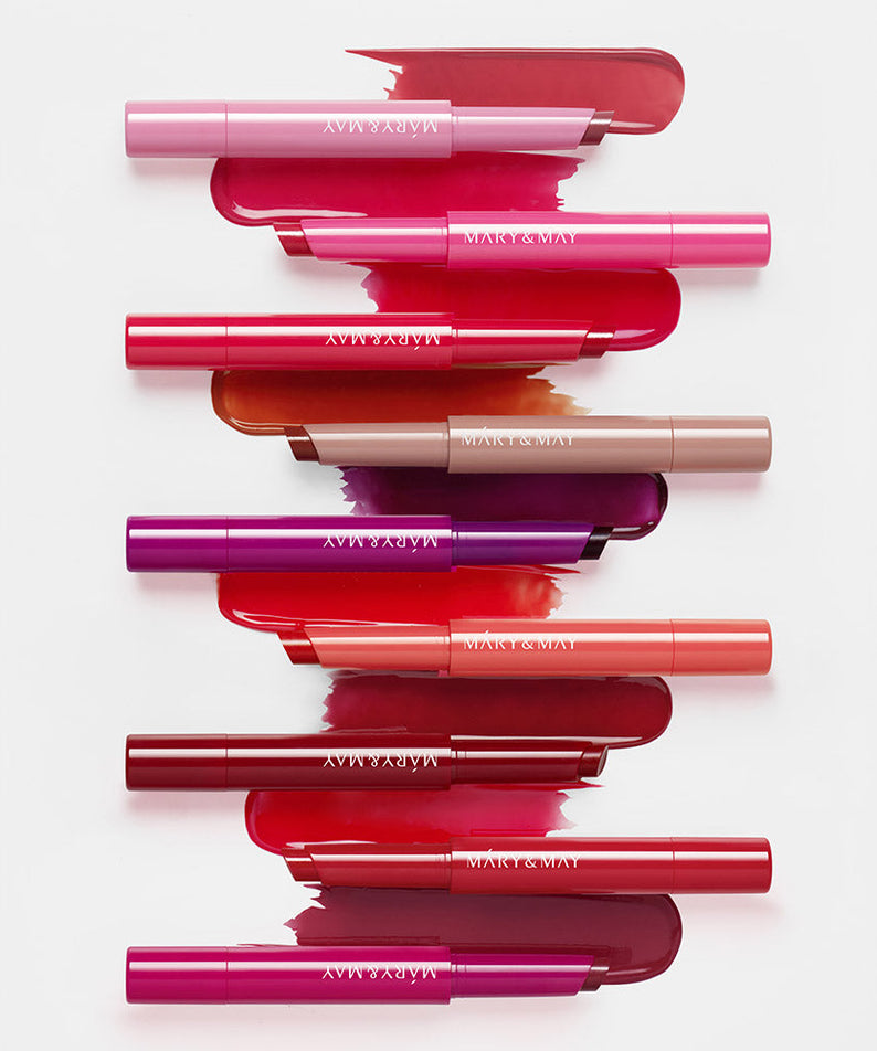 Décris l'image en français : MARY&MAY Blooming Glow Lip 09 Sunset Tangerine 1.7g, baumes colorés sur fond clair.