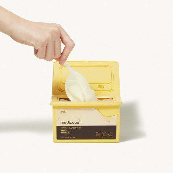 MEDICUBE Deep Vita C Daily Quick Mask 30 Sheets, main ouvre des lingettes masque en tissu, coffret jaune, contexte beauté.