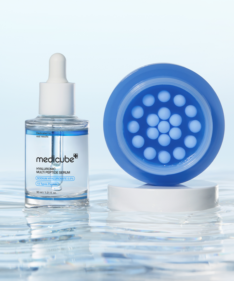 MEDICUBE Hyaluronic Moisturizing Capsule Cream 55g : sérum flacon et capsule bleue sur fond bleu, gouttes d’eau, marque MEDICUBE