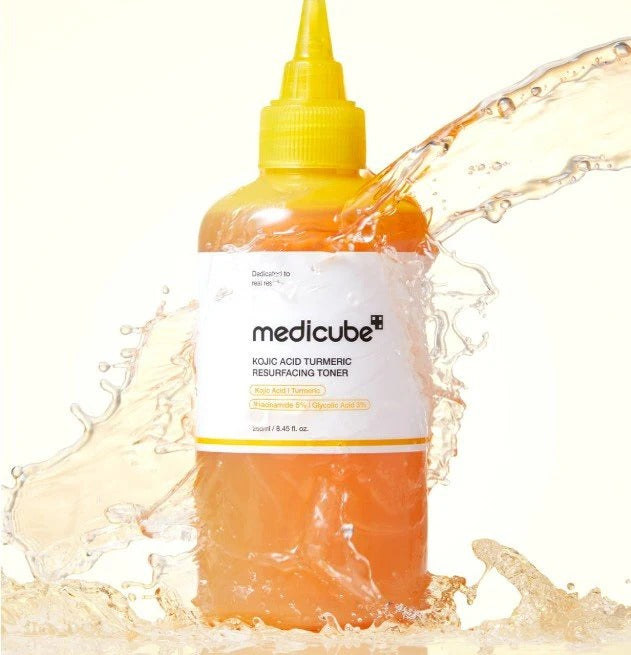 MEDICUBE Kiojic Acid Turmeric Resurfacing Toner 200ml, flacon MEDICUBE jaune dans une éclaboussure d’eau orange, fond clair.