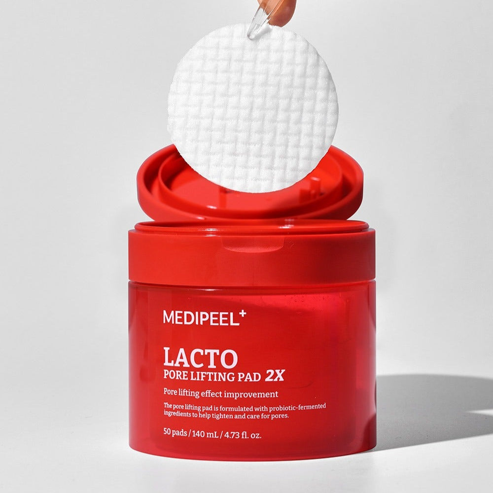 MEDIPEEL Lacto Pore Lifting Pads 2X 140ml 50 Sheets, boîte rouge avec pads blancs sur fond clair (contexte produit)