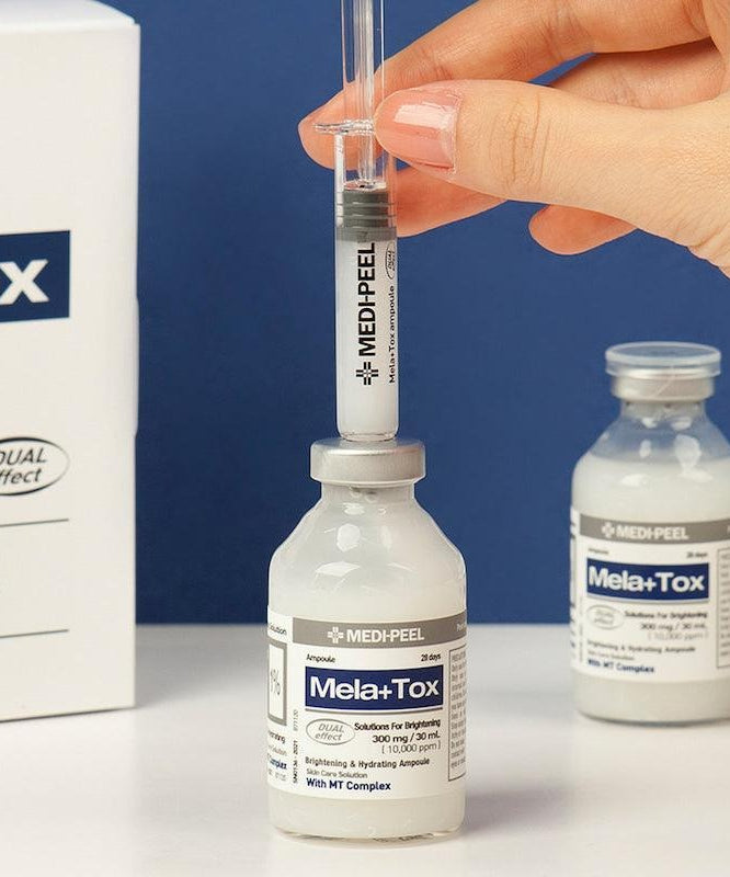 Flacon de MEDIPEEL Mela Plus Tox Ampoule 35ml avec main tenant une seringue au-dessus du flacon, produit de soin intensif.