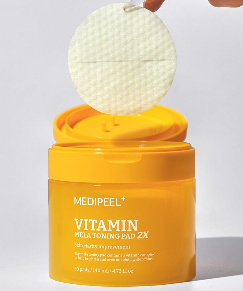 Boîte de MEDIPEEL Vitamin Mela Toning Pads 2X 140ml 50sheets ouverte avec un pad en gros plan, améliorant la clarté de la peau.