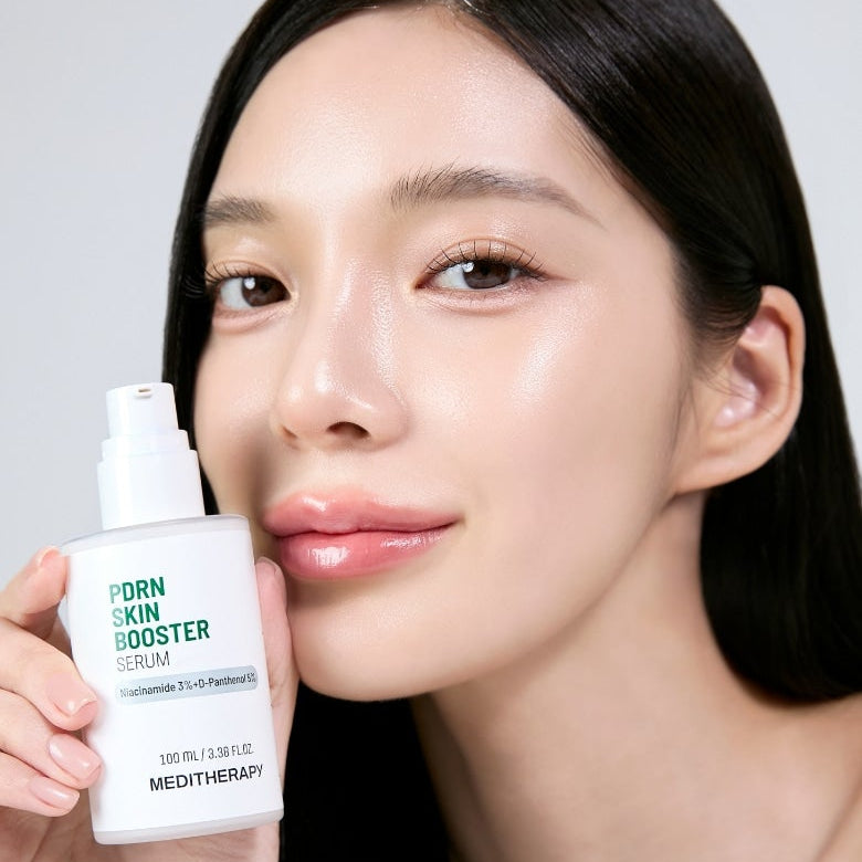 Décris l'image en français : MEDITHERAPY PDRN Skin Booster Serum 100ml de Meditherapy, visage lumineux, sérum tenu en main.