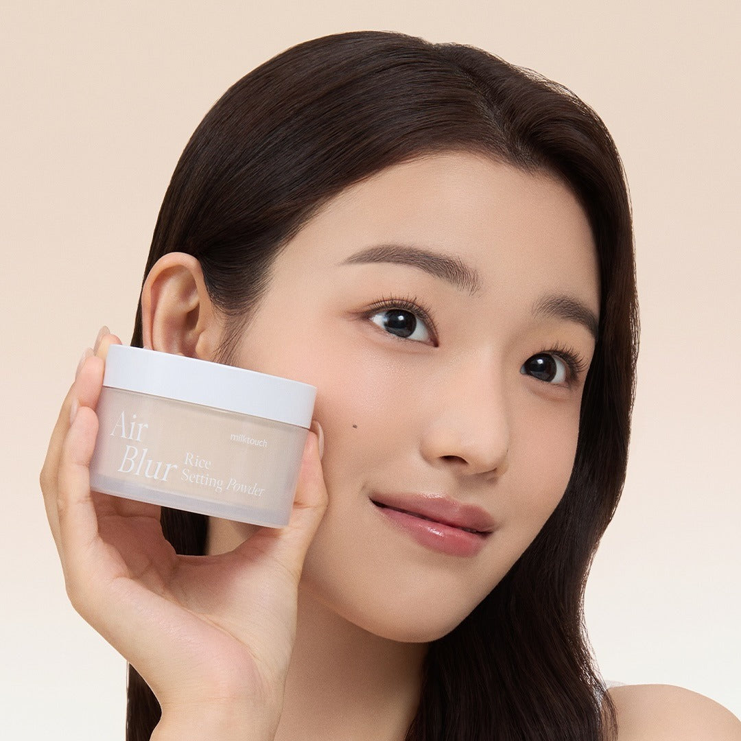 MILK TOUCH Air Blur Rice Setting Powder de la marque sur une femme, pot tenu en gros plan, peau floutée, studio