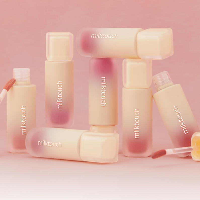 MILK TOUCH Spread Fit Blur Tint de la marque Milk Touch, flacons pastel maquillage sur fond rose doux.