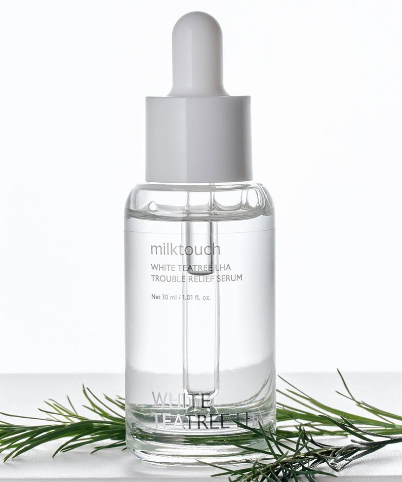 MILK TOUCH White Tea Tree Laha Trouble Relief Serum 30ml sur fond blanc avec théier, bouteille et pipette, marque visible.