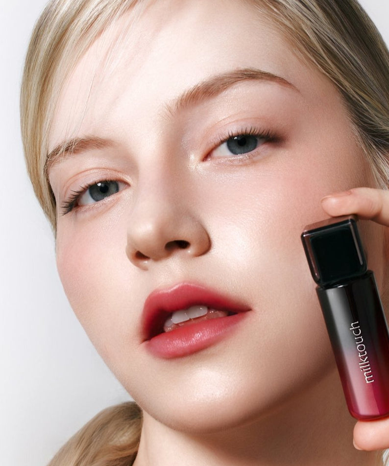 Femme avec MILK TOUCH Black Peel-Off Lip Tattoo applicateur pour des lèvres élégantes et durables en noir.