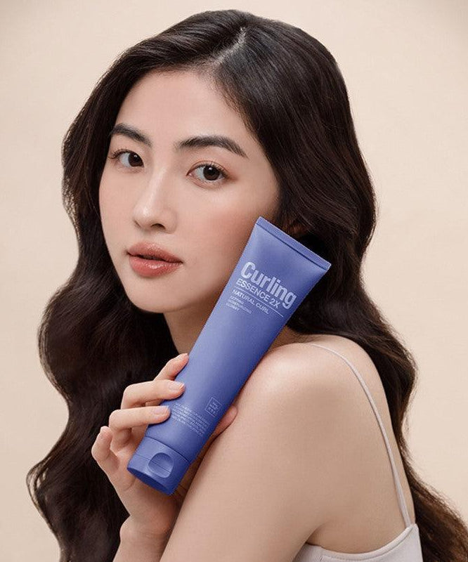 MISE EN SCENE Curling Essence 2X 150ml : tube bleu tenu par une femme aux cheveux bouclés, fond beige, branding visible.