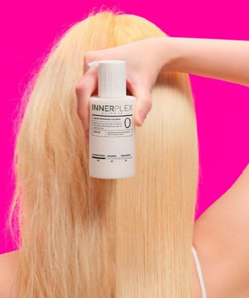 MISE EN SCENE Innerplex Hair Strengthener 145g Plan : femme tient le flacon INNЕРPLEX, fond rose, application sur cheveux