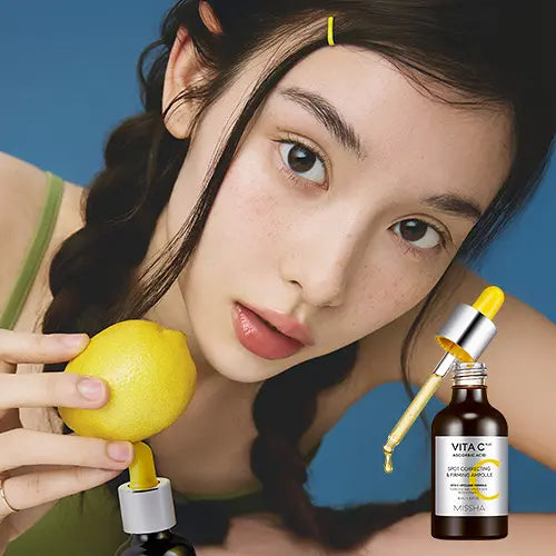 Décris l'image en français : MISSHA  Vita C Plus Blemish C Elasticity Ampoule 40ml, flacon près de citrons et d’une femme, fond bleu.