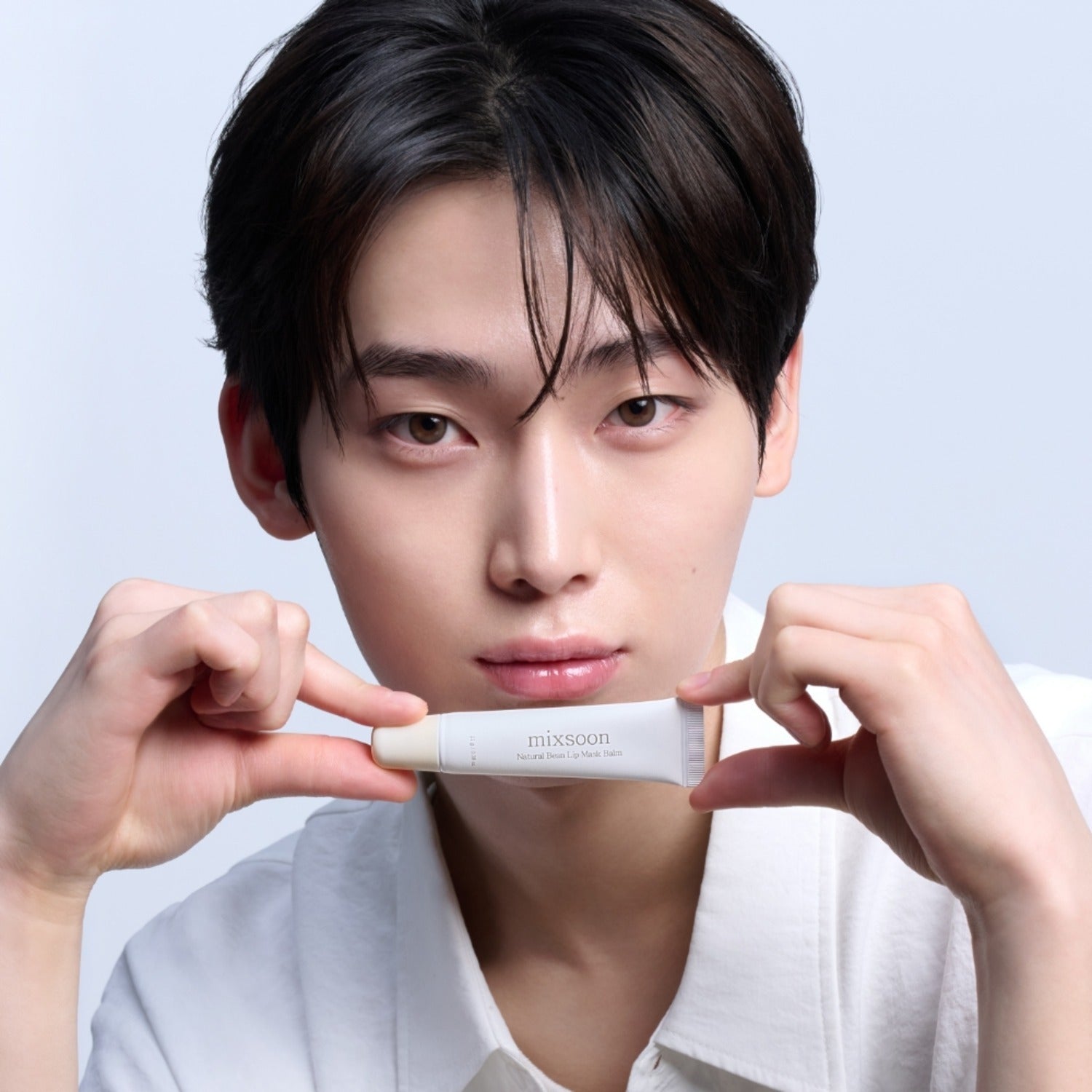 MIXSOON Natural Bean Lip Mask Bean 11g, jeune homme tenant le masque à lèvres, produit cosmétique MIXSOON sur fond clair