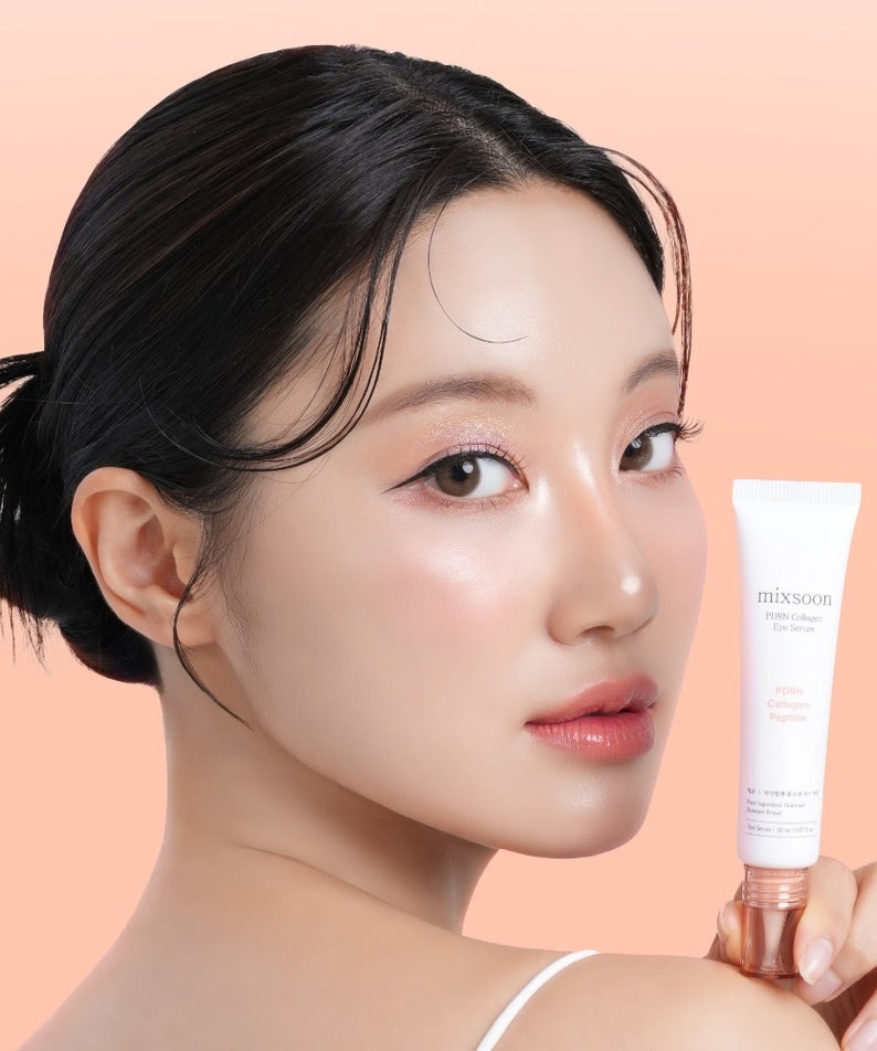 Femme souriante tenant le MIXSOON PDRN Collagen Eye Serum 20ml sur fond pêche.