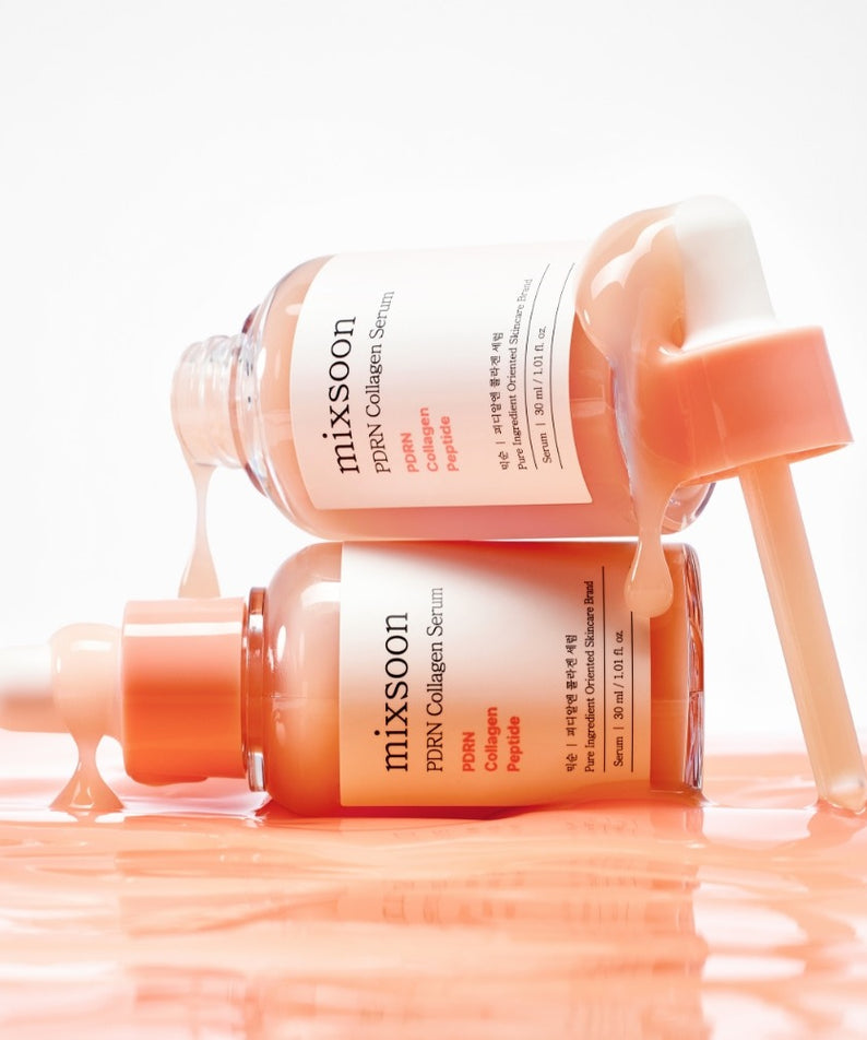 Deux bouteilles de sérum MIXSOON PDRN Collagen Serum 30ml avec pipette, posées sur une surface mouillée, avec du liquide orange.