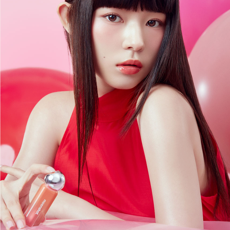 MOONSHOT Jelly Moon Glow Tint, femme maquillée sur fond rose, packaging en main, éclairage studio.