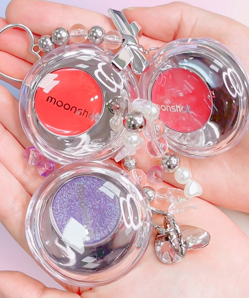 Produits cosmétiques MOONSHOT Melting Mood Lip & Cheek en trois couleurs dans la main, format pratique pour lèvres et joues.