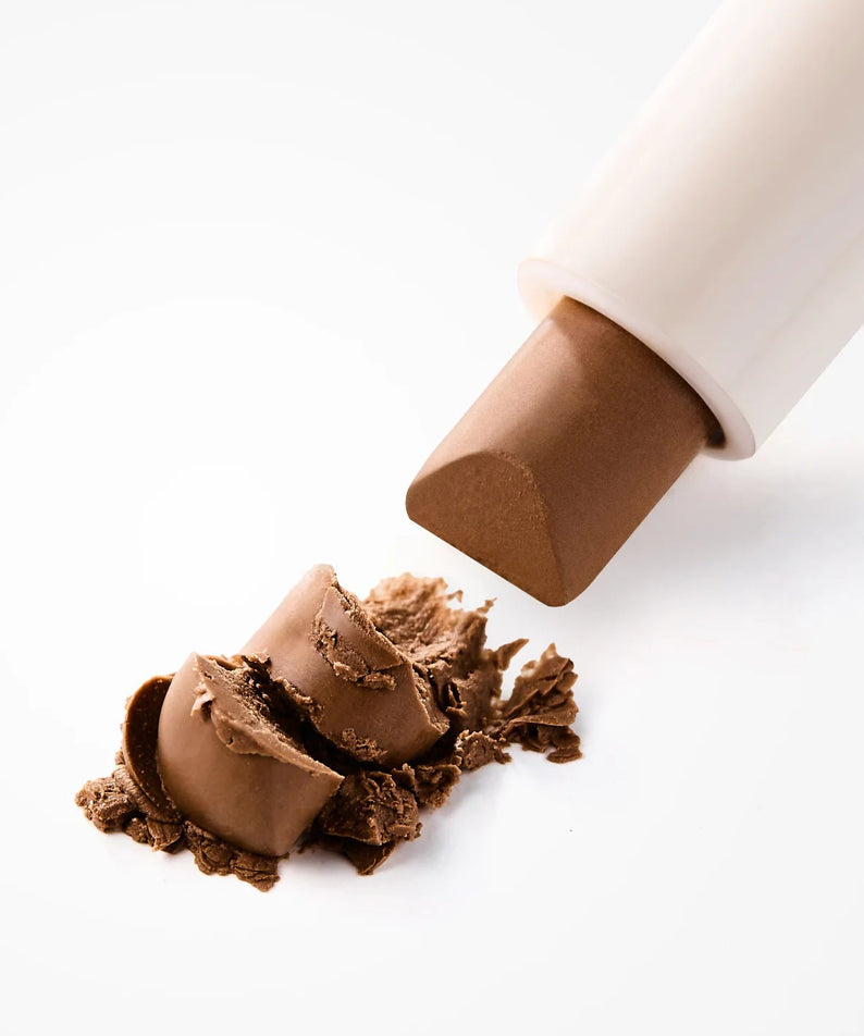 MOUMOU  Pro Contouring Noes Shading, produit de contouring près d’une peau sur fond clair, main/produit maquillage.
