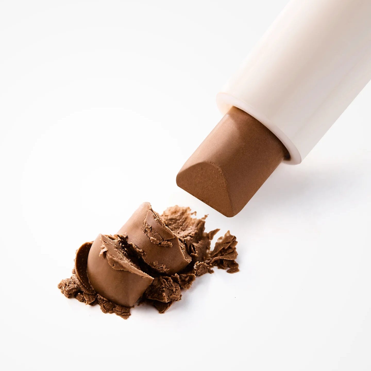 MOUMOU  Pro Contouring Noes Shading, produit de contouring près d’une peau sur fond clair, main/produit maquillage.