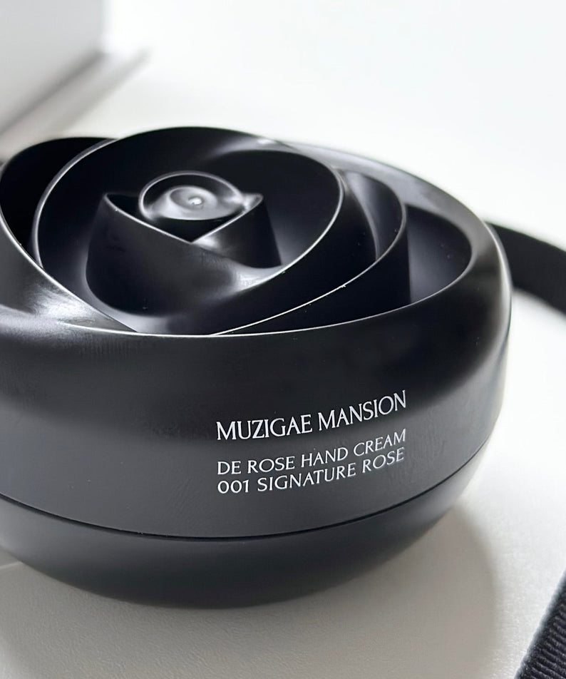 Crème pour les mains MUZIGAE MANSION De Rose Hand Cream 30g dans un pot rose noir élégant sur une table blanche.