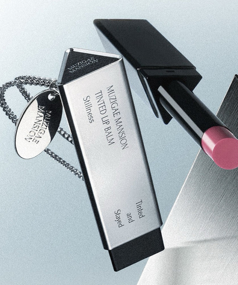 MUZIGAE MANSION Tinted Lip Balm, tube noir et baume rosé, marque MUZIGAE MANSION en gros plan sur fond clair