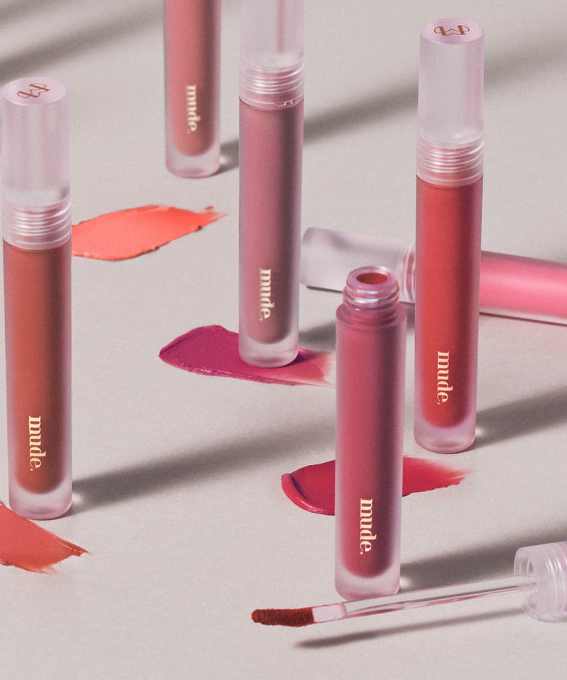 Mude Mood Soft Blur Tint de Mude, maquillage lèvres aux tons rose; produits sur fond crème avec textures.