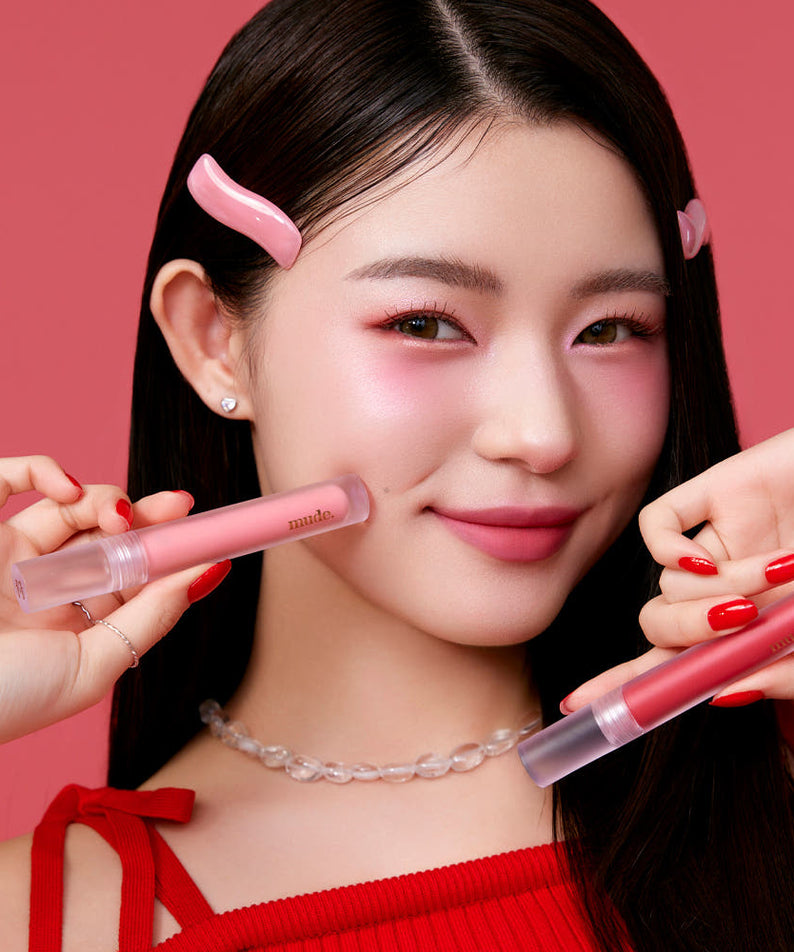Mude Mood Soft Blur Tint de Mude, sur lèvres roses, visuel maquillage en studio avec fond rouge.
