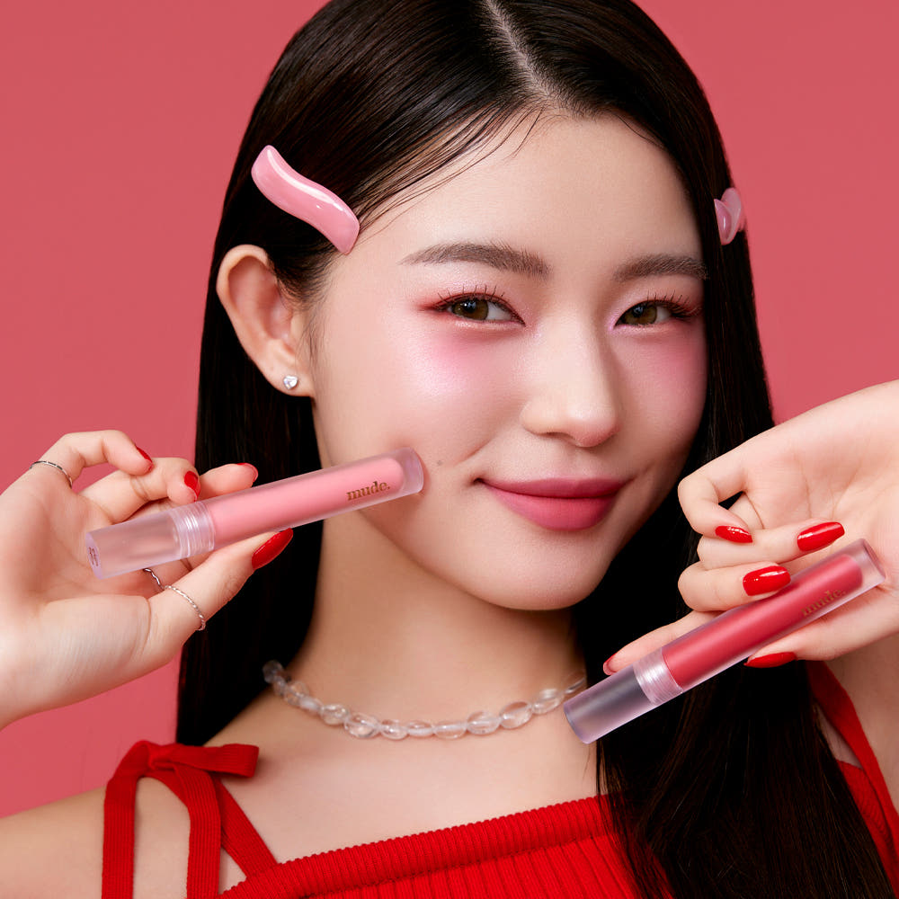 Mude Mood Soft Blur Tint de Mude, sur lèvres roses, visuel maquillage en studio avec fond rouge.
