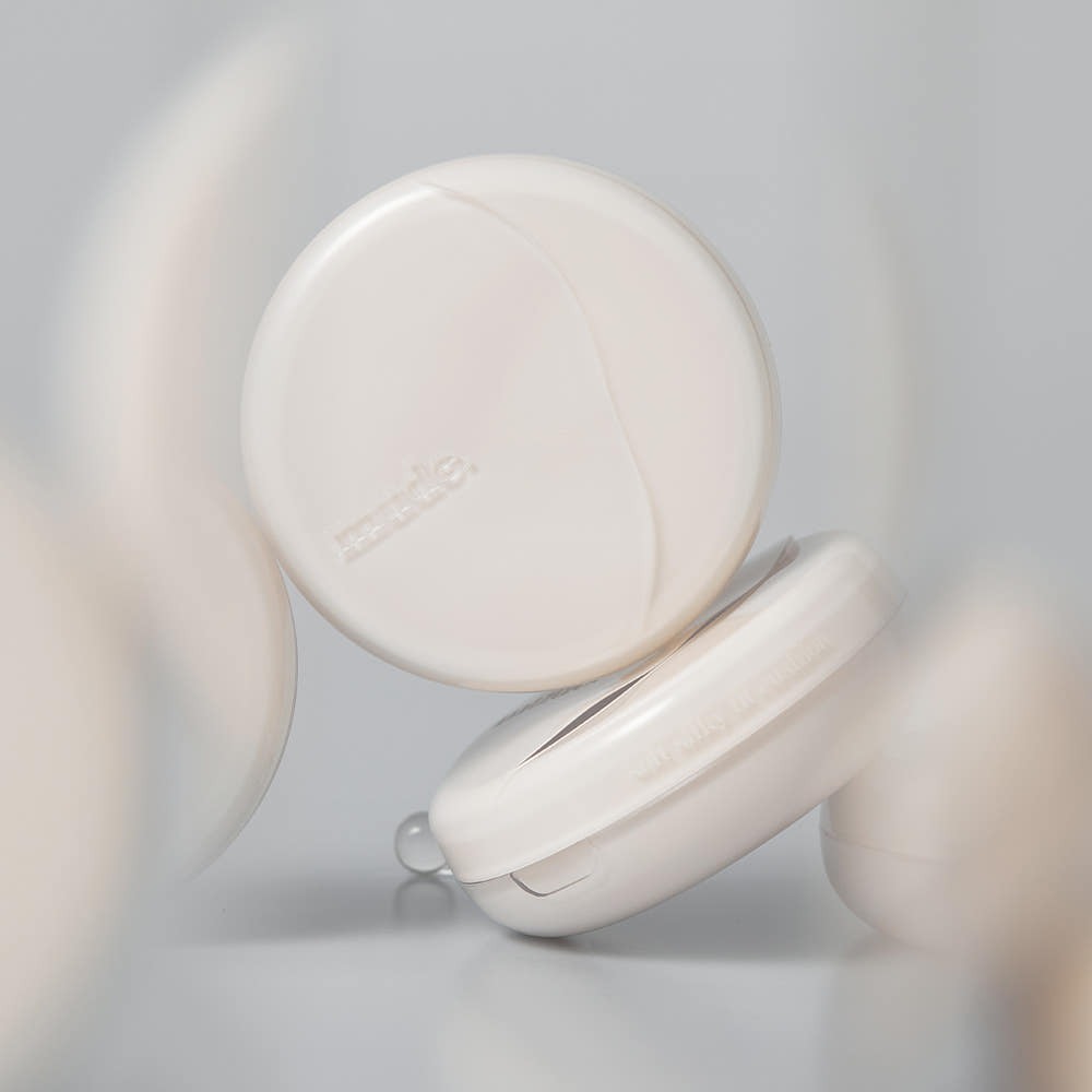 Décris l'image en français en montrant Mude Soft Silky Fit Cushion SPF50+ PA+++ Product + Refill, poudre compacte blanche.