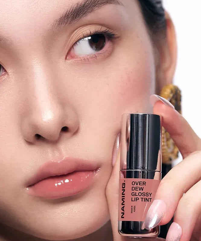 NAMING Overdew Glossy Lip Tint, marque NAMING, sur lèvres brillantes en gros plan, main tenant le tube