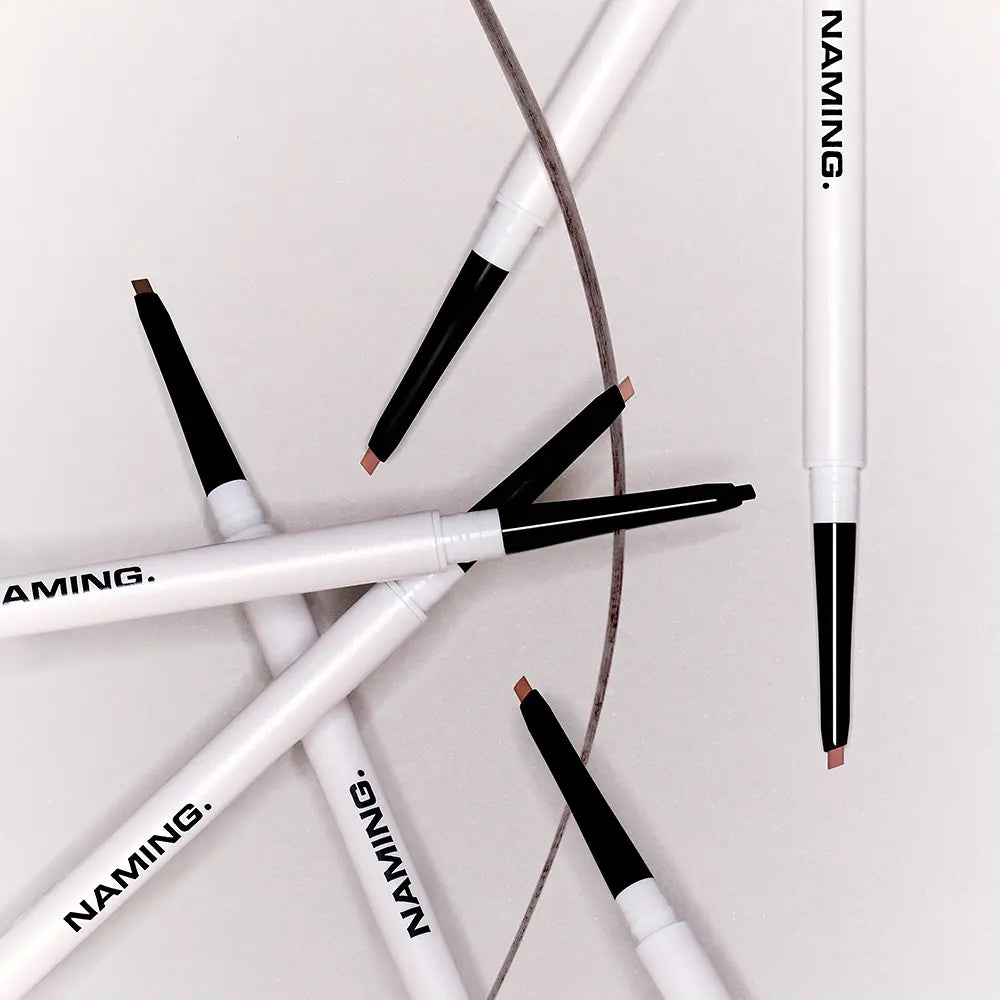 NAMING Pencil Slim Liner, stylos eyeliner noir sur fond blanc et marron, gros plan des produits NAMING.