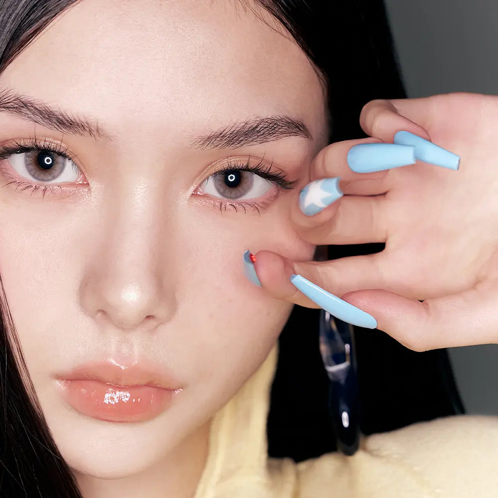 Décris l'image en français : NAMING Pencil Slim Liner, maquillage des yeux en gros plan, stylos crayon bleu, main appliquant.