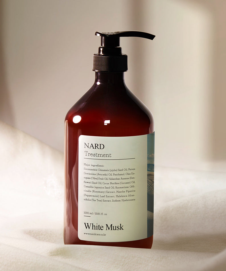 Décrivez le produit NARD Repairing Perfumed Treatment 1000ml, flacon NARD “White Musk” sur tissu beige, ambiance salle de bain.
