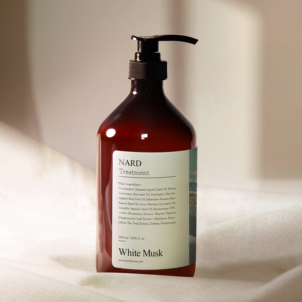 Décrivez le produit NARD Repairing Perfumed Treatment 1000ml, flacon NARD “White Musk” sur tissu beige, ambiance salle de bain.
