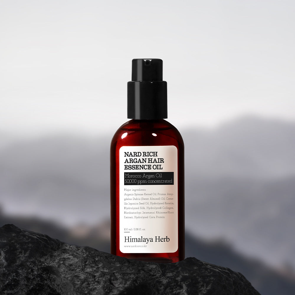 NARD Rich Argan Hair Essence Oil 100ml NARD sur pierre sombre, flacon noir et rouge, décor montagne, photo produit
