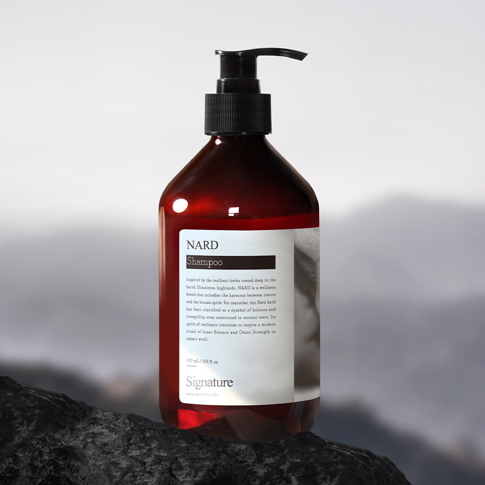 NARD Signature Shampoo 500ml de la marque NARD, flacon rouge à pompe sur rocher, fond montagne floue, photo produit