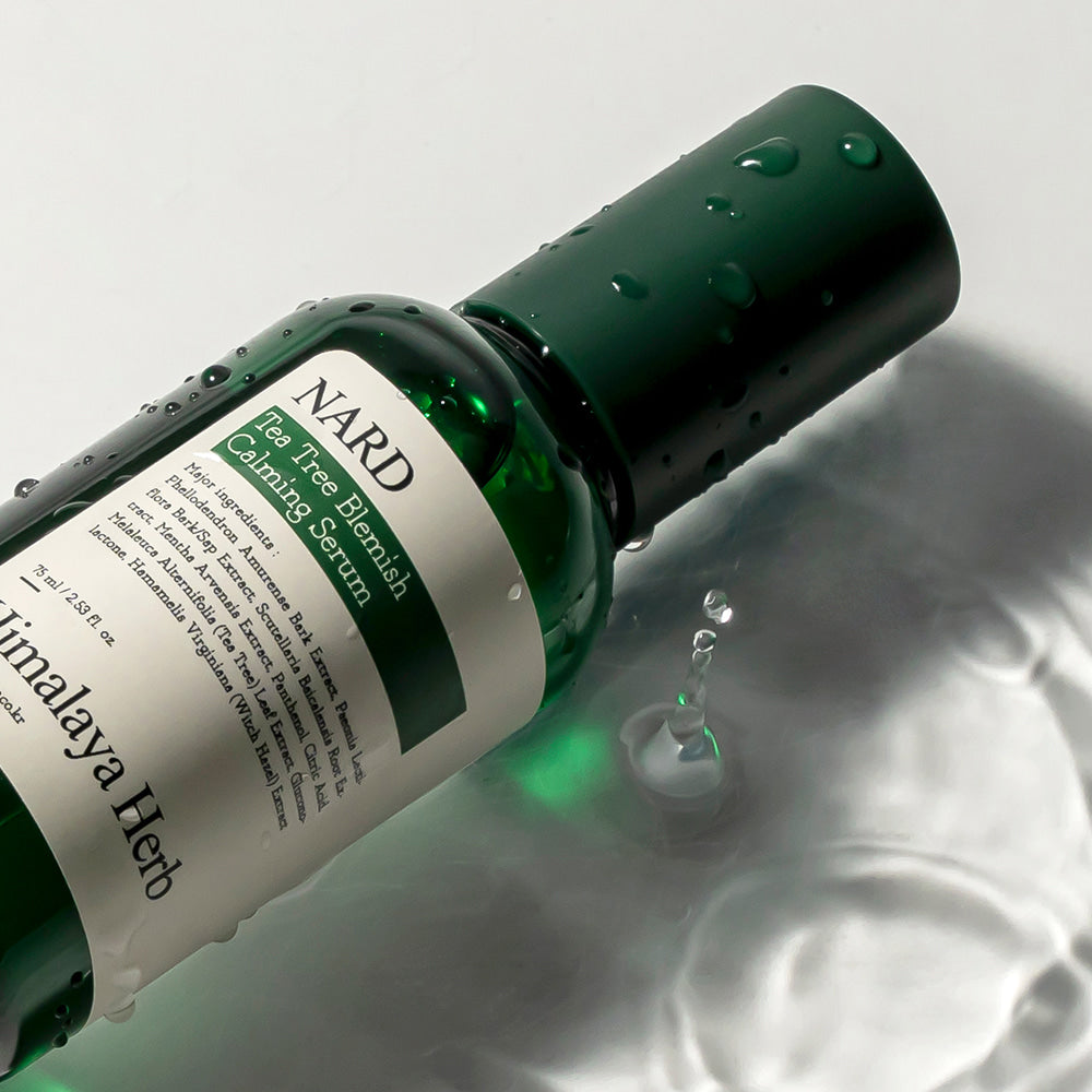 NARD Tea Tree Blemish Soothing Serum 75ml, sérum NARD au tea tree, flacon vert sur fond blanc, gouttes et reflets.