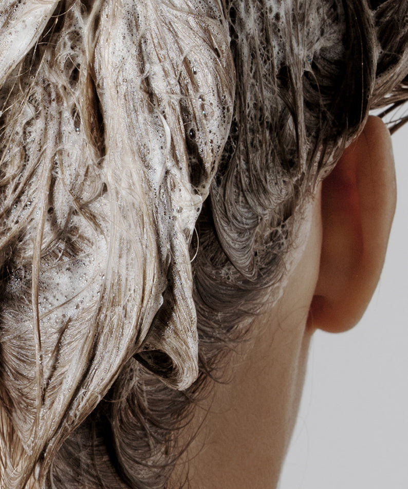Décris l'image en français : NARD Tea Tree Rosemary Shampoo 1000ml, marque NARD, mousse sur cheveux, fond clair