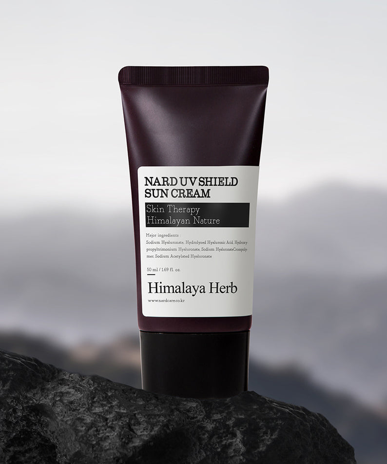 NARD UV Shield Sunscreen 50ml de NARD, tube de crème solaire sur rocher devant un paysage montagneux, lumière naturelle.