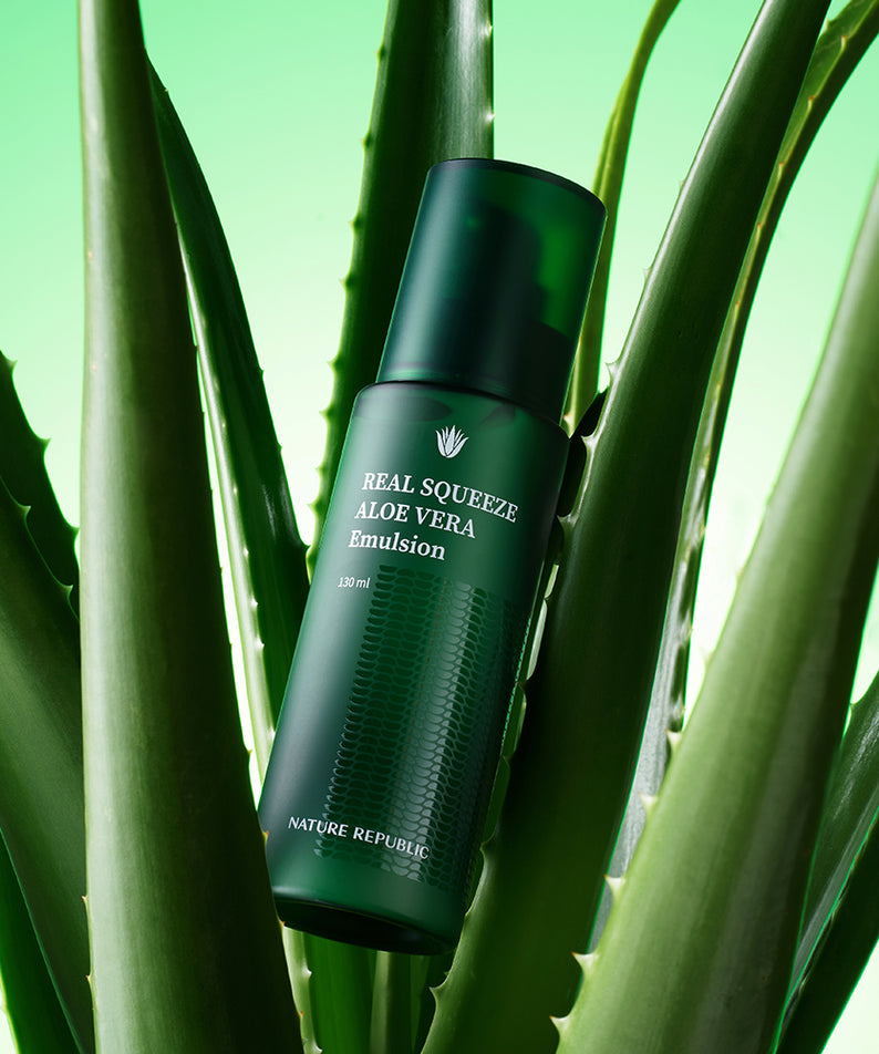 Flacon de NATURE REPUBLIC Real Squeeze Aloe Vera Emulsion 130ml parmi des feuilles d'aloès, sur fond vert.
