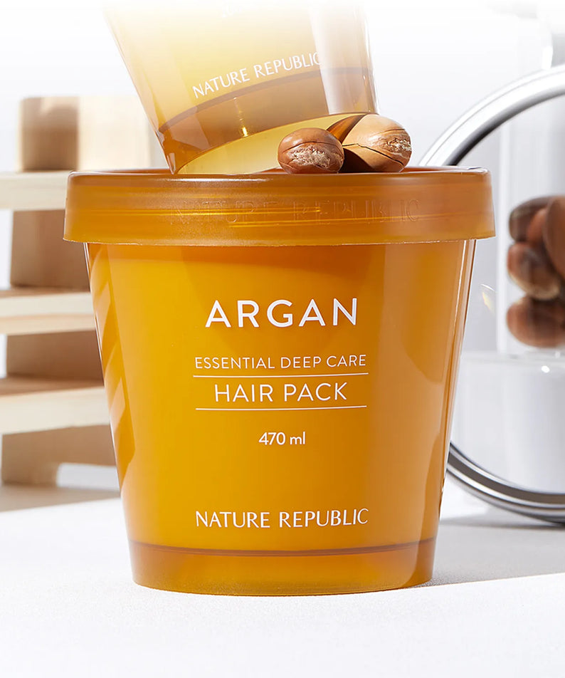 Produit capillaire NATURE REPUBLIC Essential Deep Care Hair Pack 470ml sur fond élégant avec noix d'argan en arrière-plan.