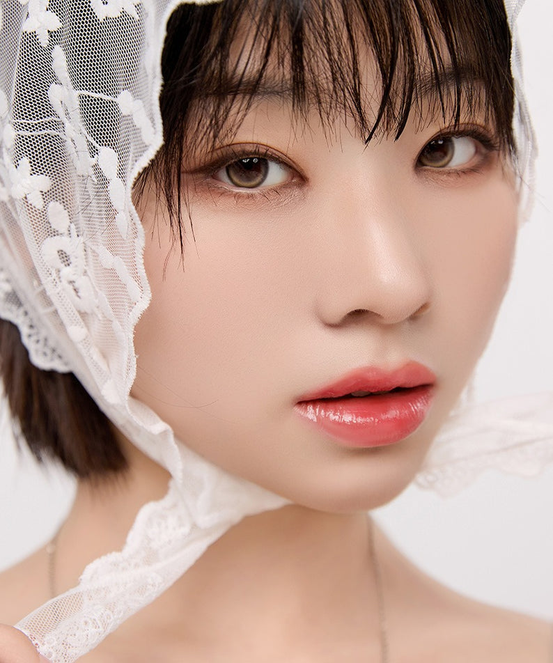 Femme portant NATURE REPUBLIC Glaze Shine Lip Oil avec éclat naturel et brillance, maquillage léger, fond blanc.