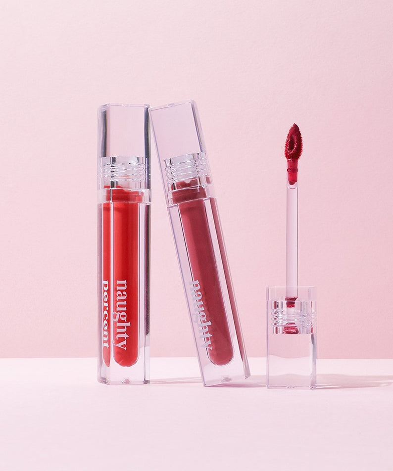 NAUGHTY PERCENT Matte Bloom Tint de la marque Naughty, sur fond rose : flacons et applicateur maquillage mat.