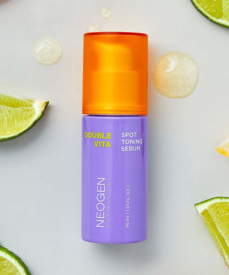 Flacon de NEOGEN Double Vita Spot Toning Serum 30ml entouré de tranches de citron vert pour une peau éclatante et tonifiée.