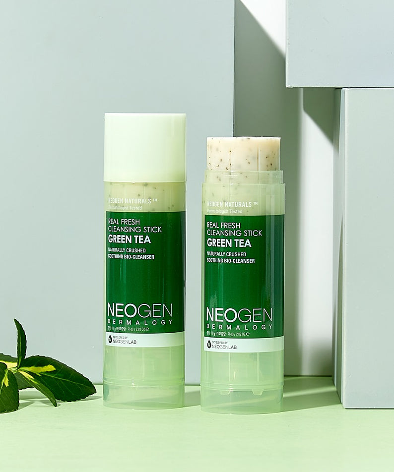 Deux sticks de nettoyage NEOGEN Real Fresh Cleansing Stick Green Tea 80g avec fond vert, branches de thé vert à côté.