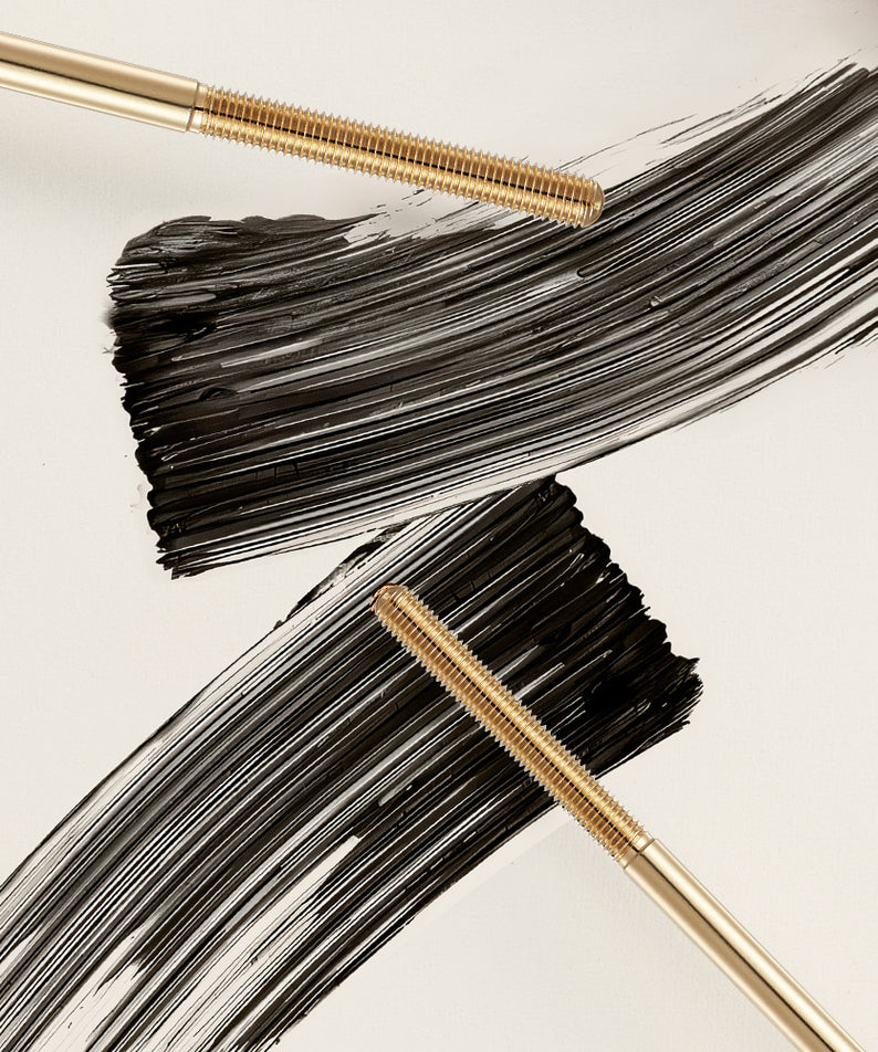 Deux brosses avec mascara sur fond blanc. NEOGEN Volumizing Metal Mascara 4ml en action, montrant des traits noirs intenses.