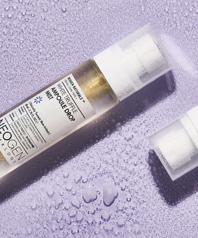 Flacon de NEOGEN White Truffle Ampoule Drop Mist 80ml sur fond violet avec gouttelettes d'eau, produit de soin riche en truffe blanche.